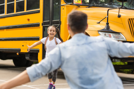Father meeting little daughter coming out of school bus