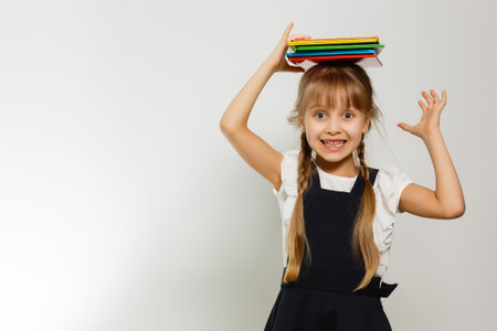 Little Funny girl in shirt with books. Isolated on white background. Baby girl in school. The child girl with textbooks. Girl studing.の写真素材