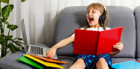 The girl at home communicates with friends on the Internet. Kids distance learning. Cute little girl...