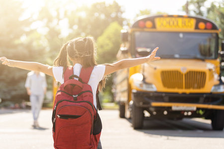 Mother brings her daughter to school near the school bus. back to school