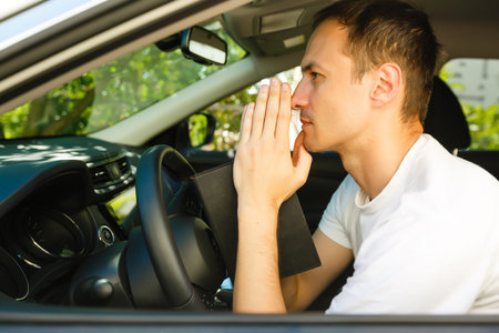 man prays with a bible in a car