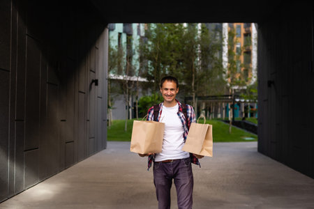 delivery, mail and people concept - happy man delivering food in disposable paper bag to customer...