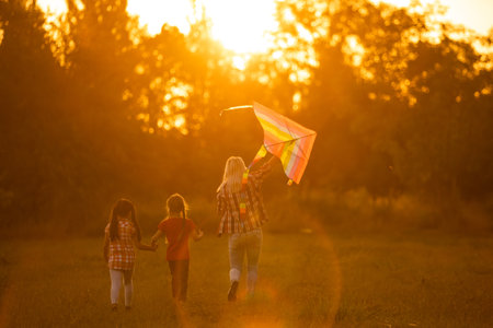 mothers and daughters in a field at sunset with an kiteの写真素材