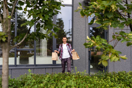 delivery, mail and people concept - happy man delivering food in disposable paper bag to customer homeの写真素材