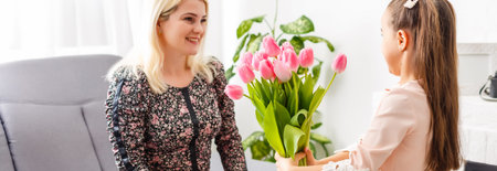 Happy mothers day. Child daughter congratulates moms and gives her flowers tulipsの写真素材