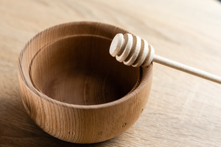 Honey with wooden honey dipper in wooden bowl on wooden tableの写真素材