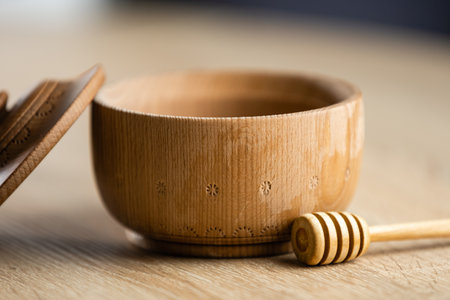 Honey dripping from honey dipper in wooden bowl. Close-up. Healthy organic. Thick honey dipping from the wooden honey spoon, closeupの写真素材