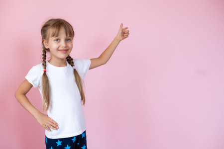 Pretty little girl in a white t-shirt smiling on a pink background