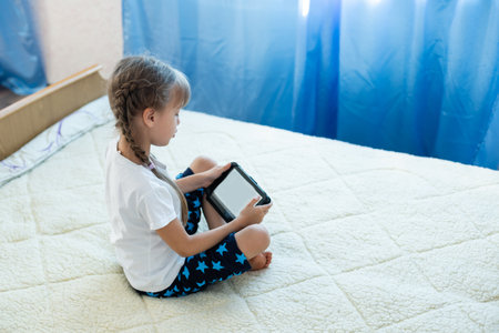 Remote lessons. The child smiles happily and gets knowledge remotely. Little girl study online learning from home with laptop. Online school.の写真素材