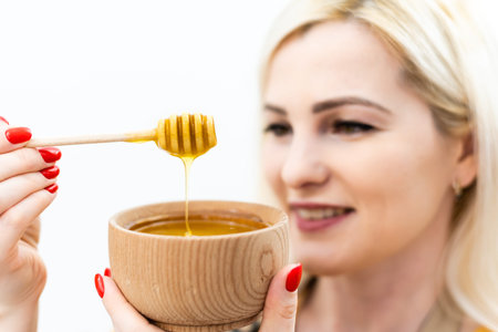 smiling young woman with bowl of honey on white background