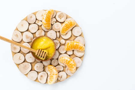 honey in a wooden bowl and orange on a white backgroundの写真素材