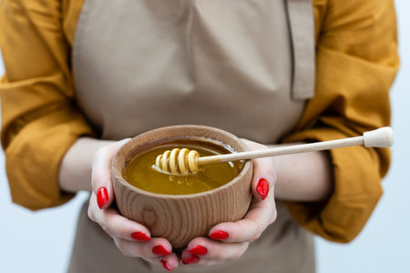 smiling young woman with bowl of honey on white background