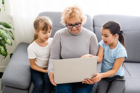 Grandmother with granddaughters use a computer