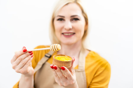 Happy young woman holding wooden bowl of honey, copy space