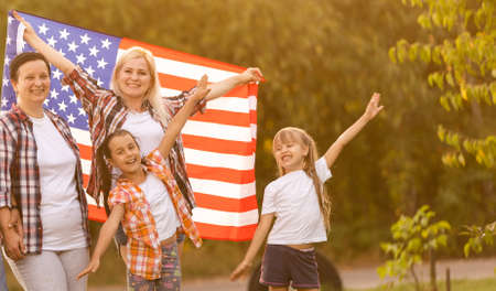 big family are walking walking american flags. Front view, american patriots on the park meadow.の写真素材