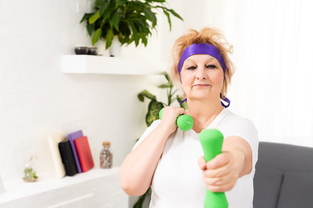 Senior woman doing physical exercises with a dumbbell