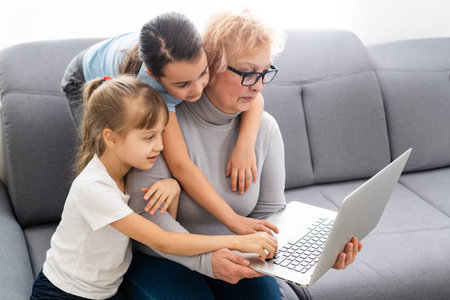 Grandmother with granddaughters use a computer
