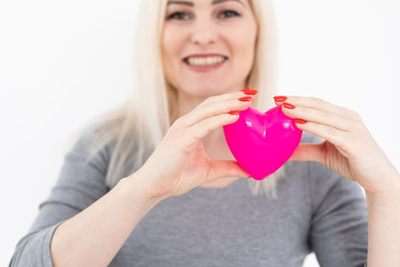 Young happy woman hold Love symbol red heart. Isolated on studio background female model.