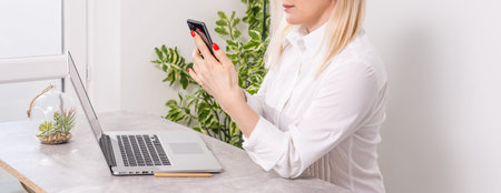 Portrait of a smiling young woman using laptop and smartphone