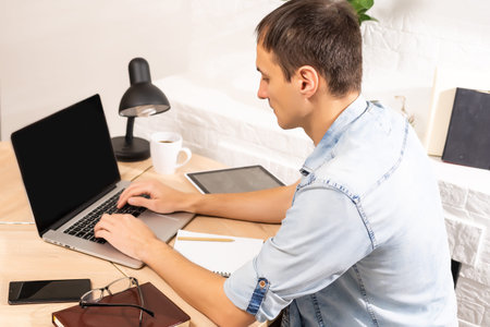 Portrait of a man working at home on some project, he is sitting at a table, drawing ideas on a...