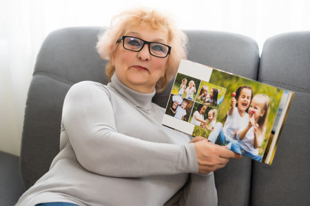 Women watching family album at home, elderly woman watching photobookの写真素材