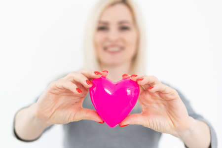 Young happy woman hold Love symbol red heart. Isolated on studio background female model.の写真素材