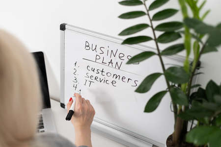 Everything must be planned. Attractive young woman writing something down on the blackboard. woman writing business planの写真素材