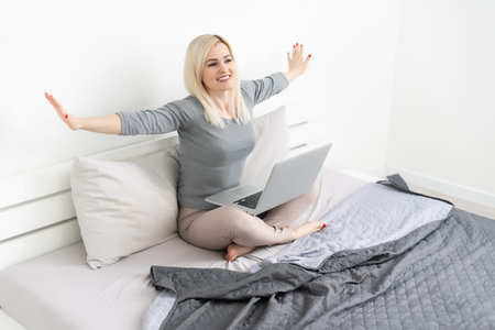 Pretty woman using her laptop in bed