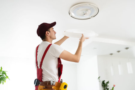 Electrician at work. Service for the repair of electrical wiring and replacement of ceiling lamps. A...