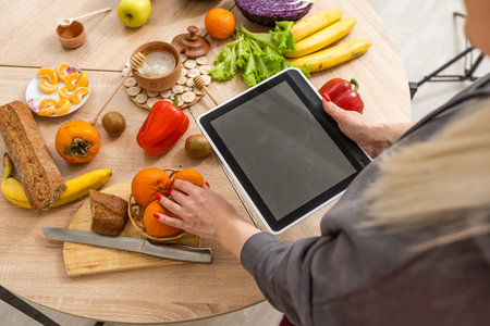 woman using tablet in her kitchen, vegetables, healthy food