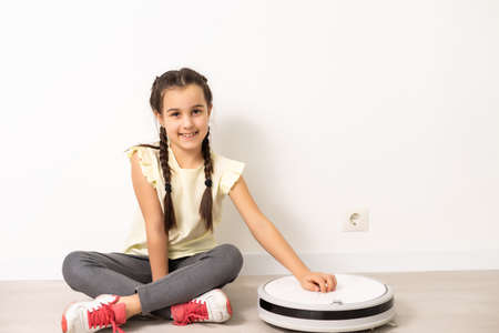 Little girl using robotic vacuum cleaner at homeの写真素材