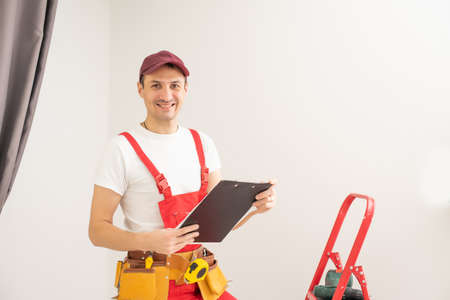 Smiling male architect with clipboard and pen against a white background.の写真素材