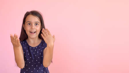 Girl playing hide and seek portrait. Cute little girl open her face with hands. Playing hide and seekの写真素材