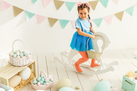 Cute little girl with bunny ears and basket of Easter eggs
