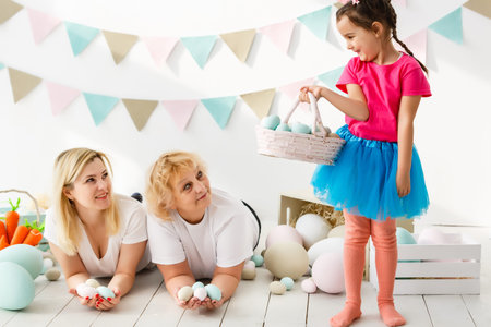Getting ready to Easter. Lovely little girl holding an Easter egg and smiling with decoration in the...