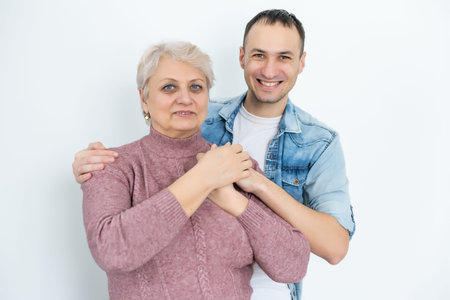 Head shot happy young bearded man embracing beautiful smiling middle aged senior mother in eyewear,...