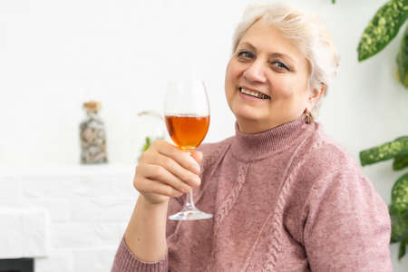 Female senior drinking red wine - isolated on white backgroundの写真素材