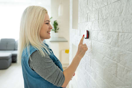 Closeup of hand pressing button on digital thermostatの写真素材