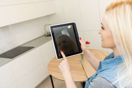 Woman use application for smart home control on tablet. Interior of living room in the backgroundの写真素材