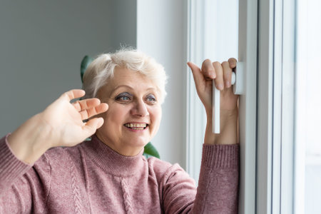 Senior woman resting at home standing near the window elderly lifestyle close-up