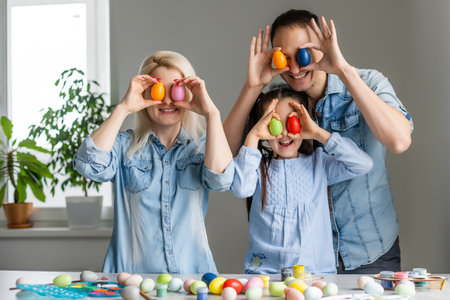 Mother, father and daughter are painting eggs. Happy family are preparing for Easter.の写真素材