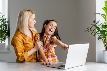 Helpful mother explaining to daughter about using a laptop