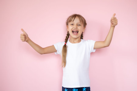 Beautiful little blonde girl with long hair in white T-shirt smiling on a pink background