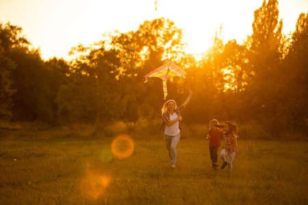 mothers and daughters in a field at sunset with an kiteの写真素材