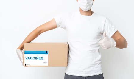 Contactless delivery during COVID-19 pandemic lockdown concept. Delivery man wearing mask and gloves holds a parcel with medical equipmentの写真素材