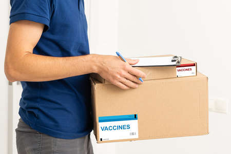 Contactless delivery during COVID-19 pandemic lockdown concept. Delivery man wearing mask and gloves holds a parcel with medical equipmentの写真素材