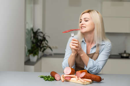 Attractive Young Woman Holding a Sausage on a Forkの写真素材