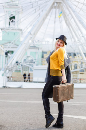 The young girl walks around the city near sights. Ferris wheel. Amusement park. autumn