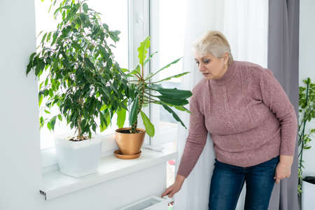 Heavy duty radiator - central heating, an elderly woman checks the heatingの写真素材
