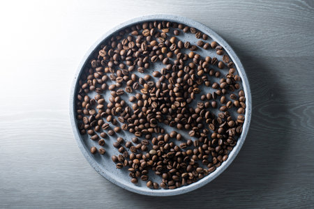 Brown roasted coffee beans falling on pile. Represent breakfast, energy, freshness or great...